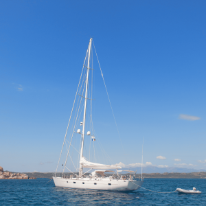 Voilier blanc amarré en mer bleue sous ciel clair.